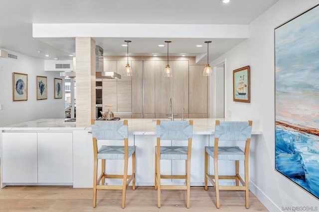 kitchen featuring light stone countertops, pendant lighting, kitchen peninsula, and a kitchen breakfast bar