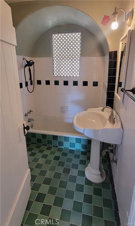 bathroom with tile walls, tile patterned flooring, and bathtub / shower combination