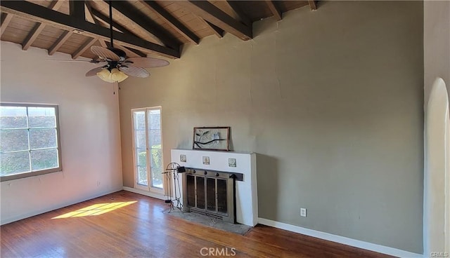 unfurnished living room with beamed ceiling, hardwood / wood-style flooring, a wealth of natural light, and wooden ceiling