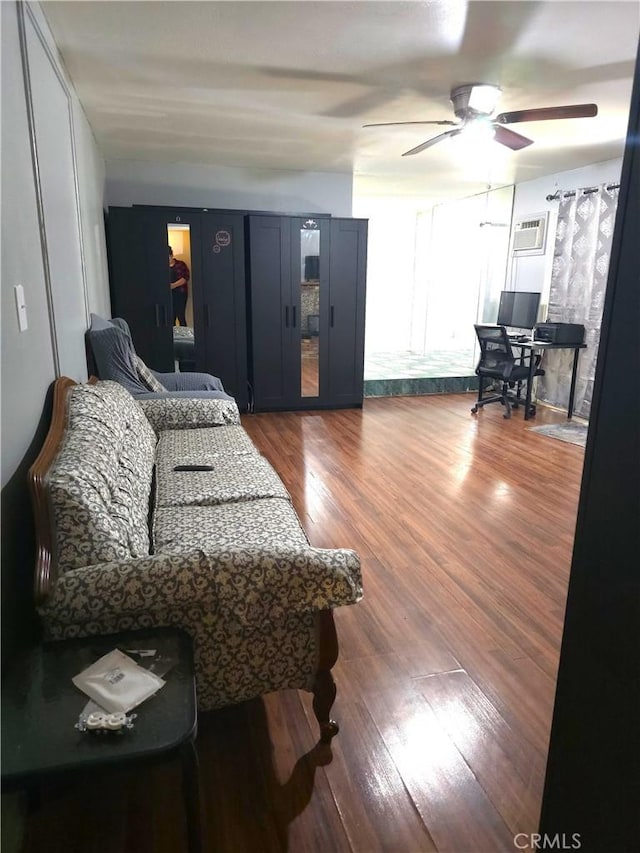 living room with dark hardwood / wood-style floors, ceiling fan, and a wall mounted AC