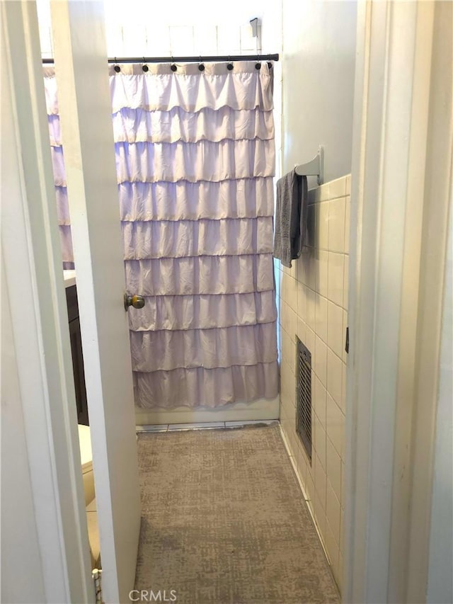 bathroom featuring shower / bathtub combination with curtain and tile walls