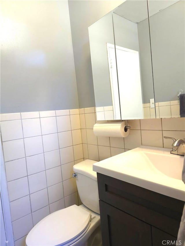 bathroom with vanity, toilet, and tile walls