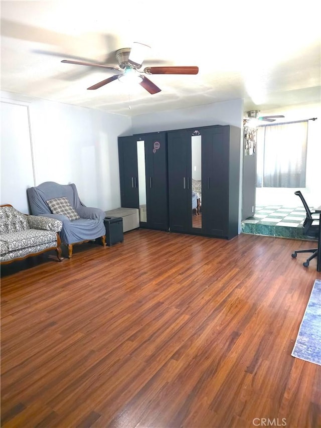 living area featuring ceiling fan and dark wood-type flooring