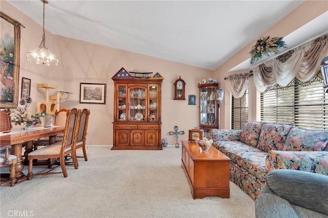 carpeted living room with a notable chandelier and vaulted ceiling