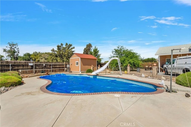 view of swimming pool with a patio, a storage shed, and a water slide