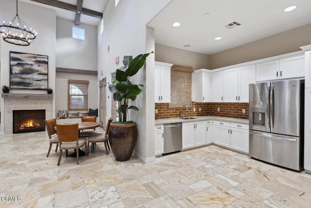 kitchen featuring white cabinetry, plenty of natural light, beamed ceiling, and appliances with stainless steel finishes