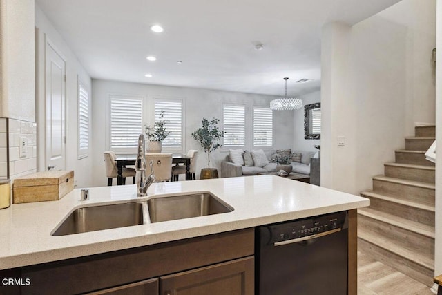 kitchen featuring dark brown cabinetry, sink, light hardwood / wood-style flooring, black dishwasher, and hanging light fixtures