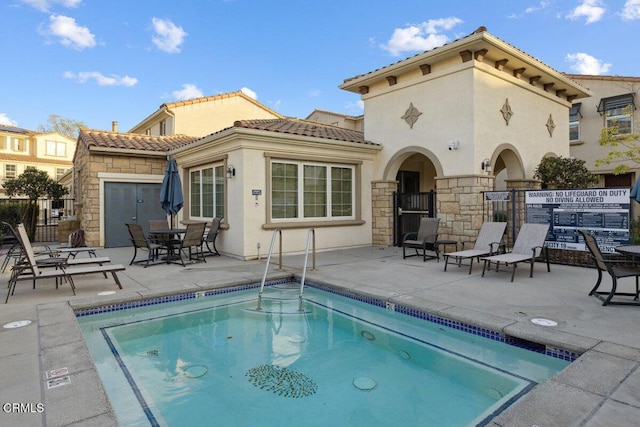 back of property featuring a patio area and a swimming pool