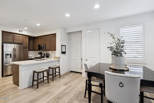 kitchen featuring sink, light hardwood / wood-style floors, dark brown cabinets, and appliances with stainless steel finishes