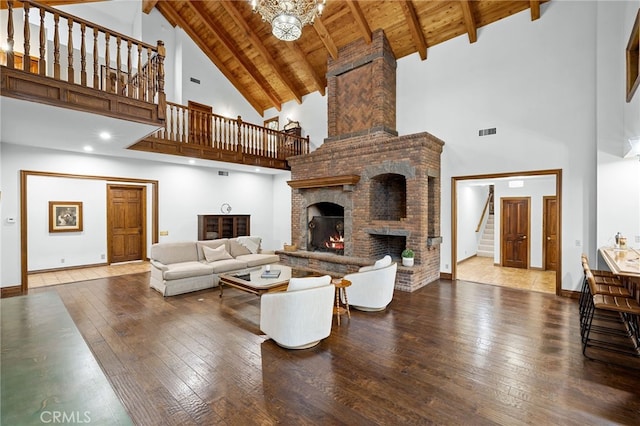 living room with high vaulted ceiling, beam ceiling, a large fireplace, and hardwood / wood-style floors