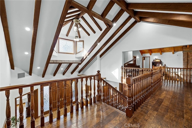 stairway featuring beam ceiling, hardwood / wood-style floors, and high vaulted ceiling