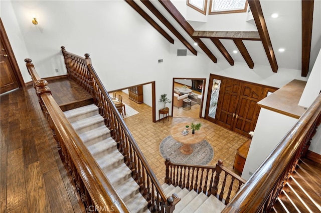 stairway with high vaulted ceiling, wood-type flooring, and beamed ceiling