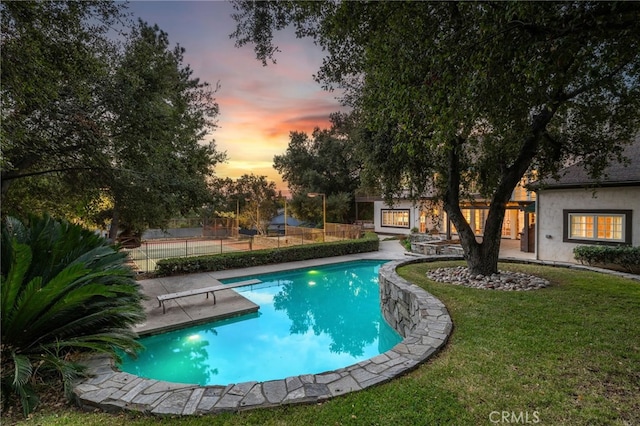 pool at dusk with a diving board and a yard