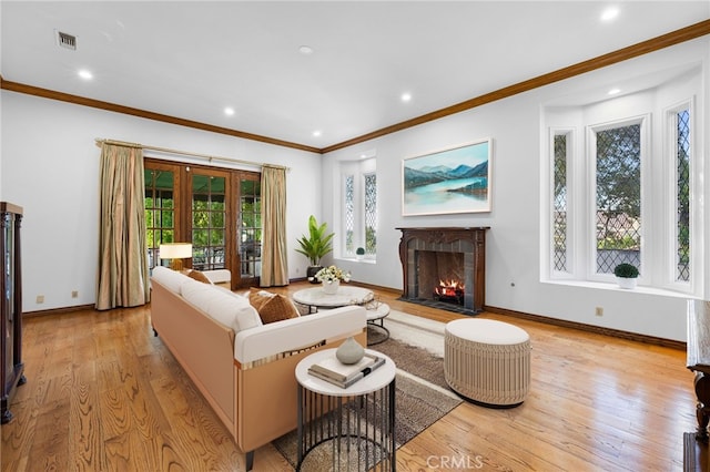 living room featuring a wealth of natural light, crown molding, and light hardwood / wood-style floors