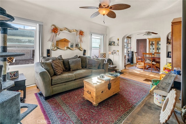 living room featuring arched walkways, wood finished floors, and ceiling fan