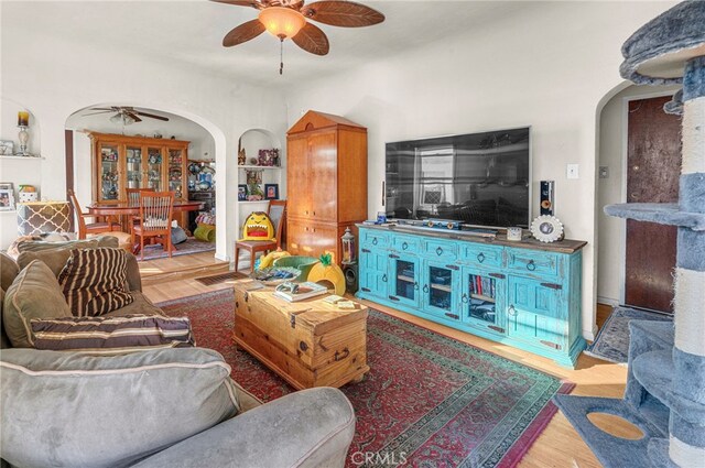 living room with light hardwood / wood-style floors, built in features, and ceiling fan