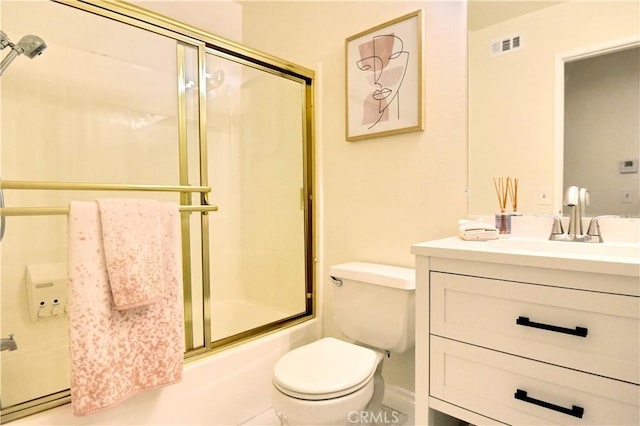 full bathroom featuring vanity, combined bath / shower with glass door, and toilet