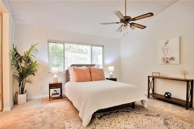 bedroom featuring ceiling fan, light colored carpet, lofted ceiling, and a textured ceiling