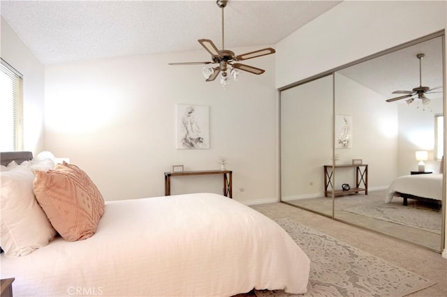 carpeted bedroom featuring a textured ceiling, a closet, ceiling fan, and lofted ceiling