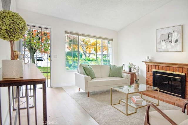 living room featuring a fireplace, hardwood / wood-style floors, a textured ceiling, and lofted ceiling