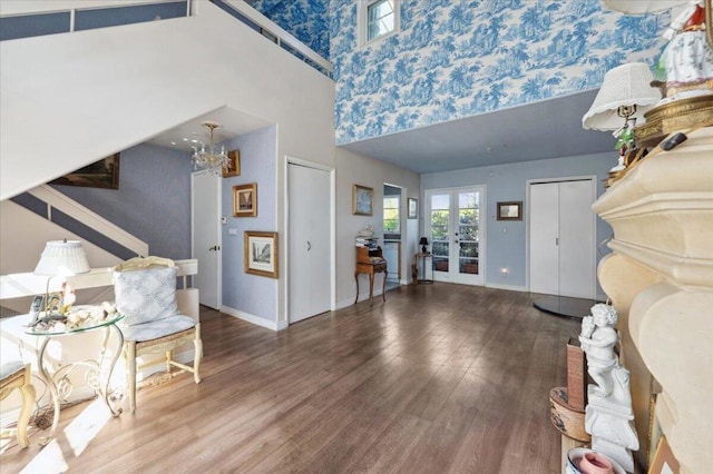 foyer featuring wood-type flooring, a towering ceiling, and french doors