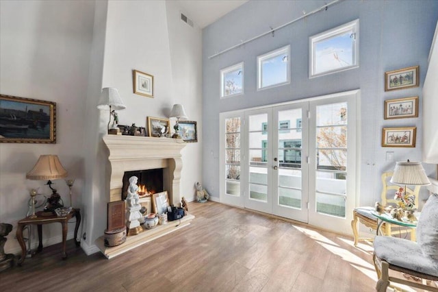 interior space with hardwood / wood-style flooring, a towering ceiling, and french doors