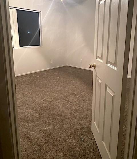 spare room with dark colored carpet