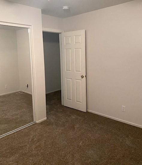 unfurnished bedroom with a closet and dark carpet