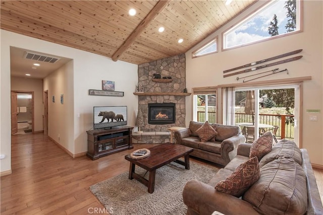 living room featuring beam ceiling, wooden ceiling, a stone fireplace, high vaulted ceiling, and light wood-type flooring