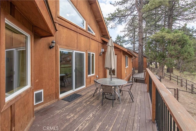 wooden terrace with outdoor dining space, fence, and visible vents