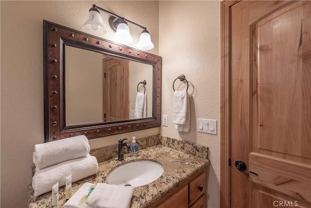 bathroom with a textured wall and vanity