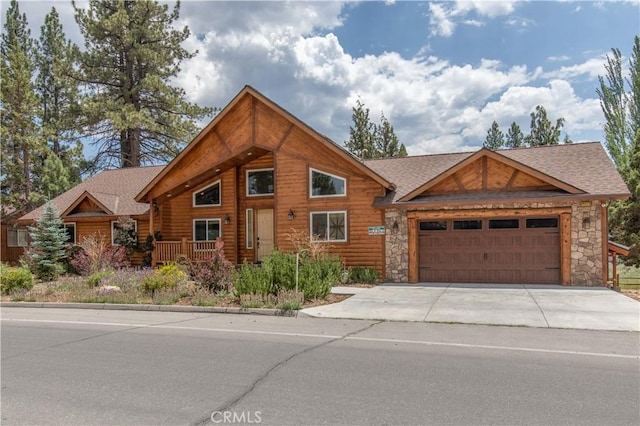 view of front of property featuring an attached garage, stone siding, driveway, and a shingled roof