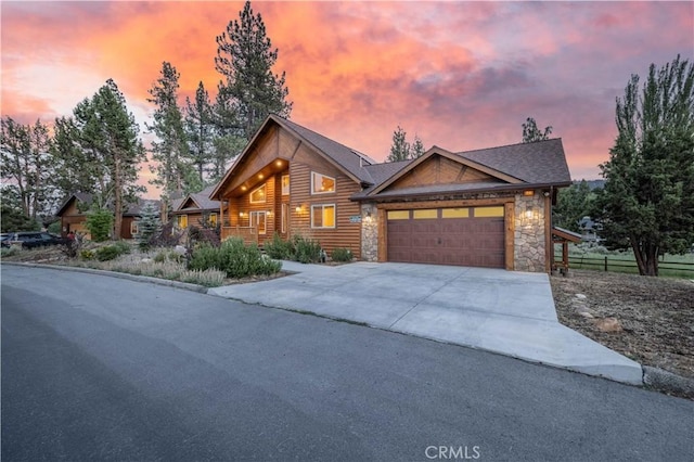 view of front facade featuring driveway, stone siding, and an attached garage