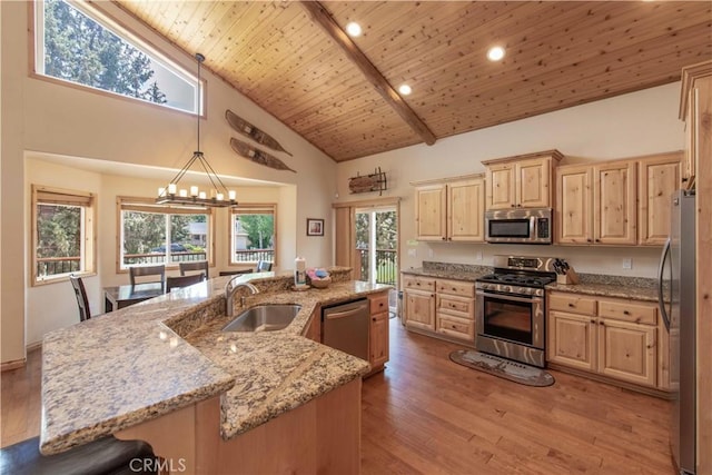 kitchen featuring a sink, light wood-style floors, appliances with stainless steel finishes, a large island, and light brown cabinetry