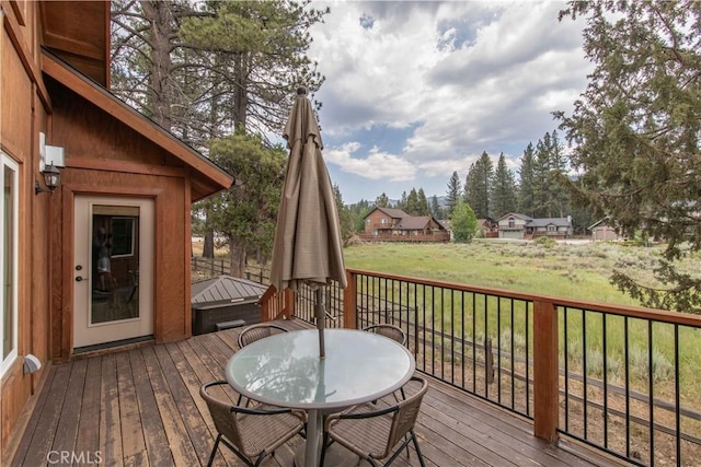 wooden deck featuring outdoor dining area and a lawn