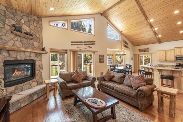 living room featuring light wood-type flooring, wooden ceiling, a fireplace, and a healthy amount of sunlight