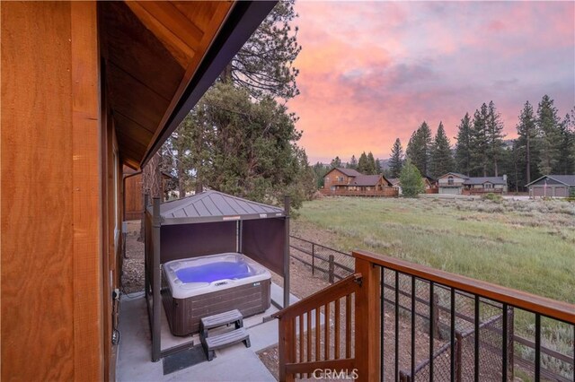 deck at dusk featuring a hot tub