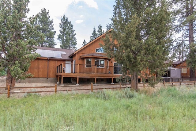 back of property with solar panels and a deck