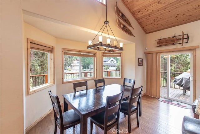 dining space featuring hardwood / wood-style flooring, lofted ceiling, a wealth of natural light, and an inviting chandelier