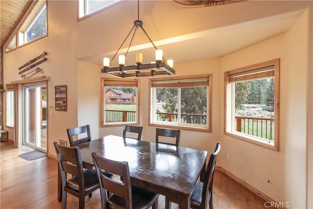 dining area with a healthy amount of sunlight, a notable chandelier, baseboards, and wood finished floors