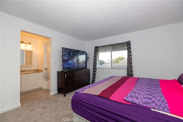 bedroom featuring a textured ceiling, light colored carpet, and ensuite bath