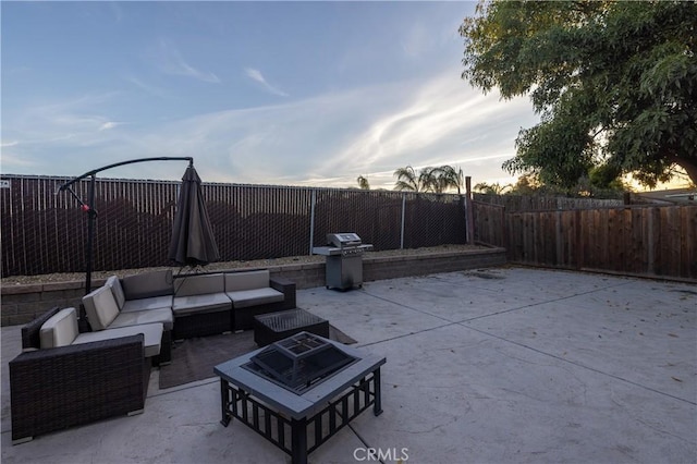 patio terrace at dusk featuring grilling area and an outdoor living space with a fire pit