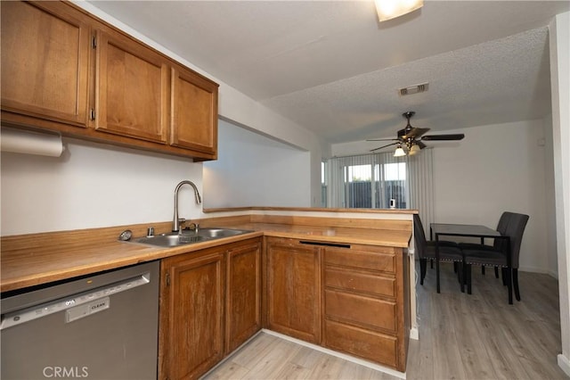 kitchen featuring ceiling fan, dishwasher, sink, light hardwood / wood-style floors, and a textured ceiling