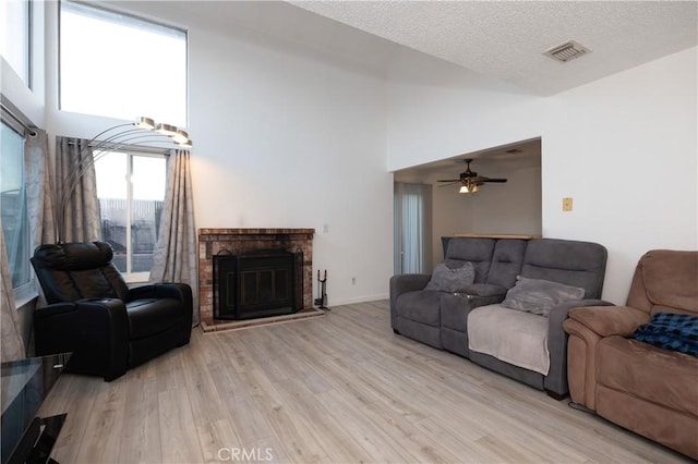 living room with light hardwood / wood-style floors, a textured ceiling, and a high ceiling