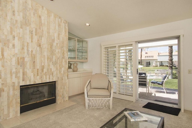 living area featuring a tile fireplace, light carpet, and lofted ceiling