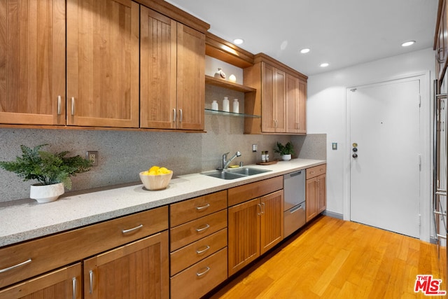 kitchen with dishwasher, sink, light stone countertops, light wood-type flooring, and tasteful backsplash