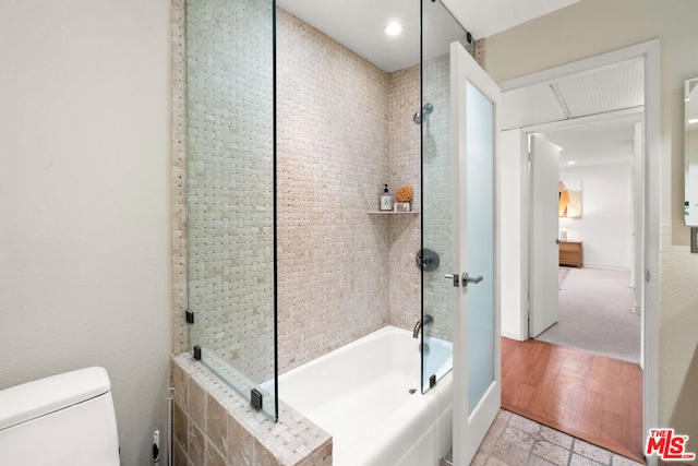 bathroom featuring toilet, enclosed tub / shower combo, and hardwood / wood-style flooring