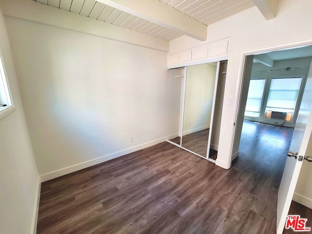 unfurnished bedroom with beam ceiling, a closet, and dark hardwood / wood-style flooring