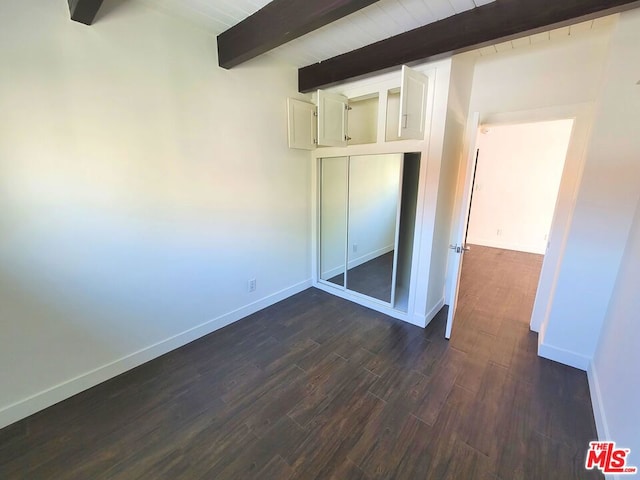 unfurnished bedroom featuring beam ceiling and dark wood-type flooring