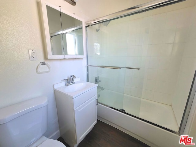 full bathroom with hardwood / wood-style floors, vanity, toilet, and bath / shower combo with glass door